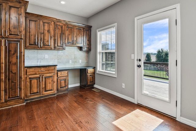 kitchen featuring dark hardwood / wood-style floors, backsplash, and built in desk