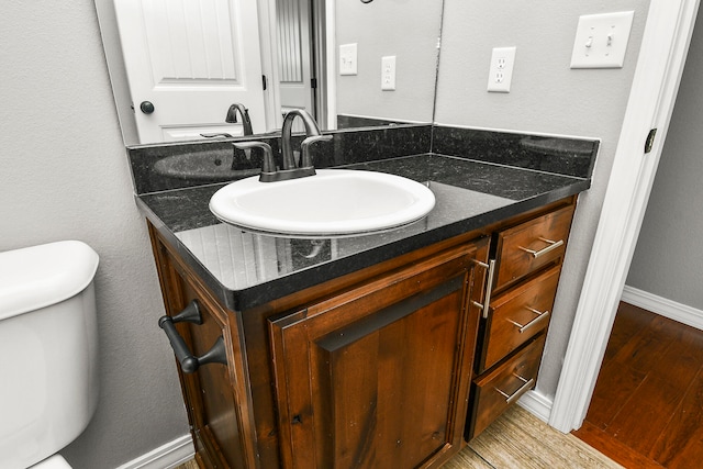 bathroom with hardwood / wood-style floors, toilet, and vanity