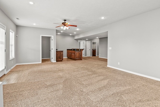 unfurnished living room featuring light carpet and ceiling fan