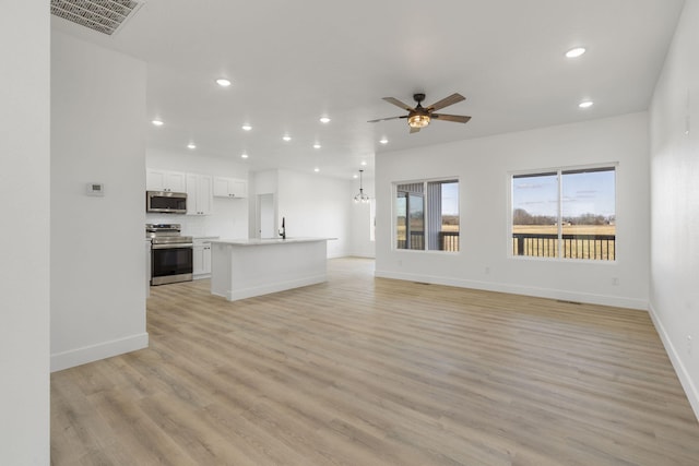 unfurnished living room with ceiling fan, sink, and light hardwood / wood-style flooring