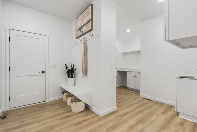 mudroom featuring light wood-style floors, a sink, and baseboards