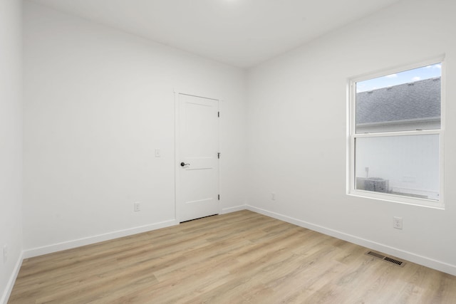 unfurnished room featuring light wood-style flooring, visible vents, and baseboards