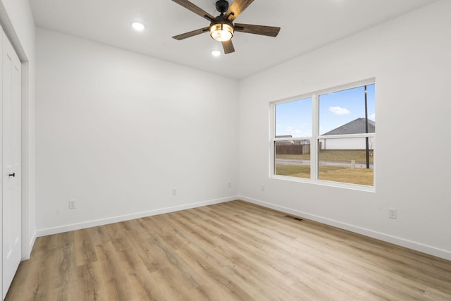 spare room with a ceiling fan, light wood-style flooring, visible vents, and baseboards