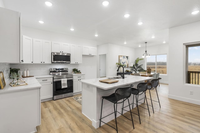 kitchen with stainless steel appliances, light wood-type flooring, a sink, and decorative backsplash