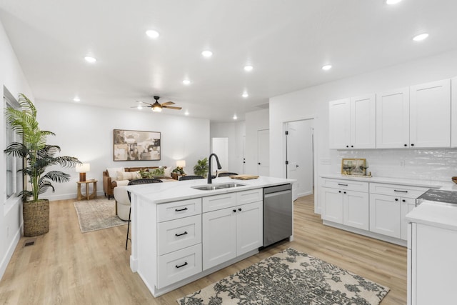 kitchen featuring a center island with sink, stainless steel dishwasher, light wood-style floors, white cabinetry, and a sink