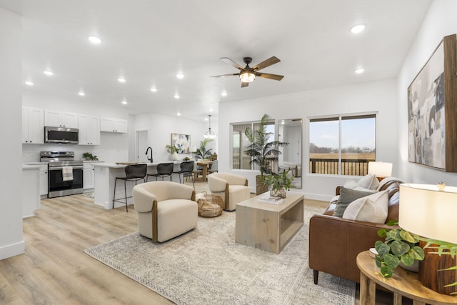 living area featuring a ceiling fan, recessed lighting, light wood-style flooring, and baseboards