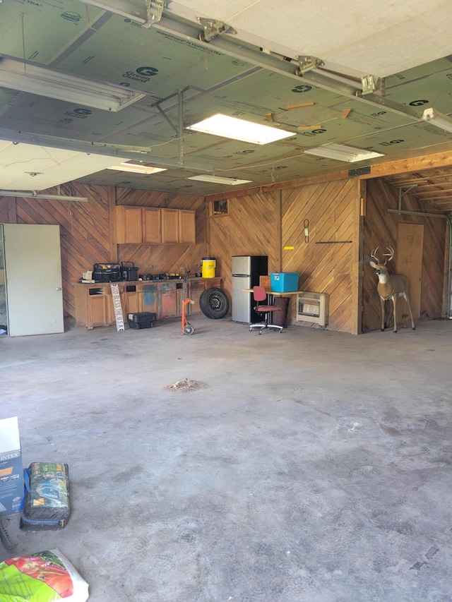 garage with stainless steel refrigerator and wooden walls