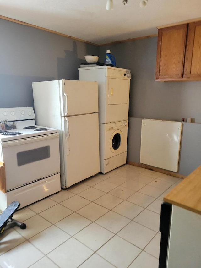 kitchen featuring light tile patterned floors, white appliances, and stacked washing maching and dryer