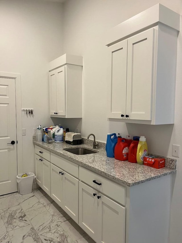 kitchen featuring white cabinets, sink, and light stone counters