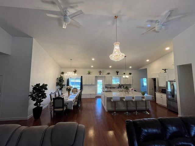 living room with ceiling fan with notable chandelier, high vaulted ceiling, and dark hardwood / wood-style floors