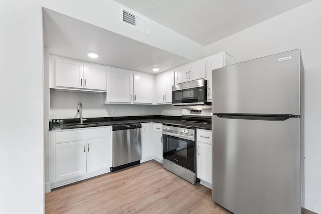 kitchen featuring visible vents, white cabinetry, stainless steel appliances, and a sink
