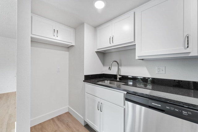 kitchen featuring dishwasher, white cabinets, dark stone countertops, and a sink