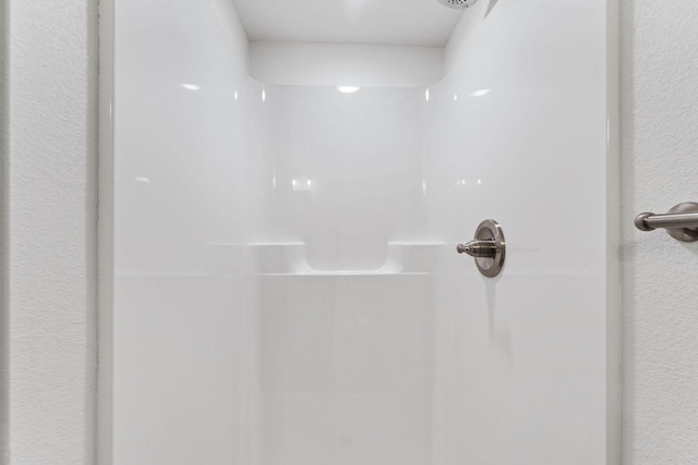 room details featuring a textured wall and walk in shower