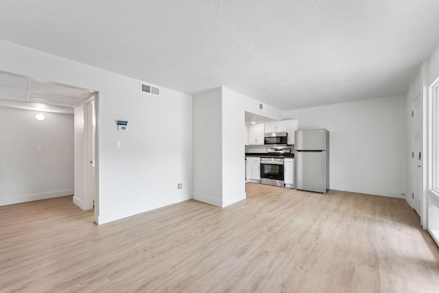 unfurnished living room featuring visible vents, light wood finished floors, and baseboards