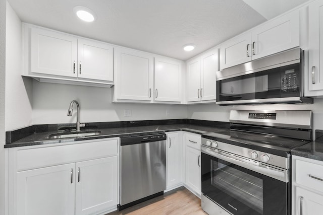 kitchen with white cabinets, light wood-type flooring, stainless steel appliances, and a sink