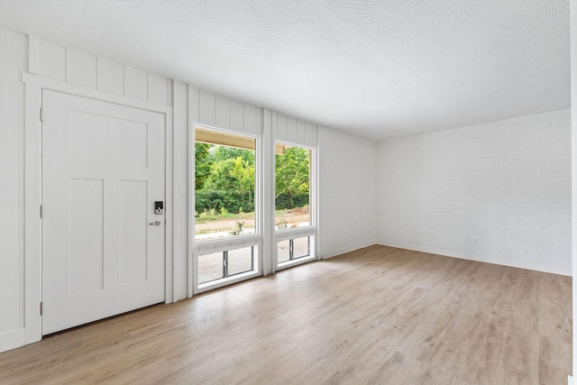 unfurnished living room with brick wall and light wood-style floors