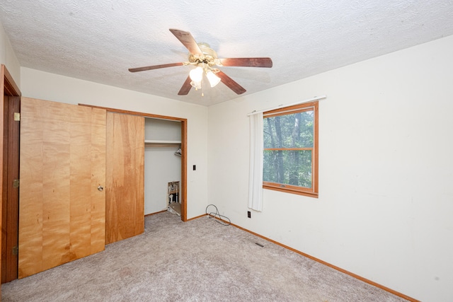 unfurnished bedroom featuring a closet, light colored carpet, a textured ceiling, and ceiling fan