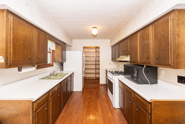 kitchen with white appliances, sink, dark hardwood / wood-style flooring, and a textured ceiling