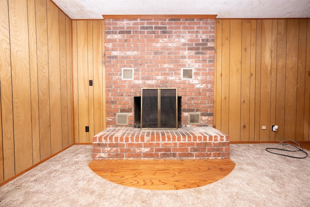 interior details featuring a brick fireplace, a textured ceiling, wood walls, and carpet