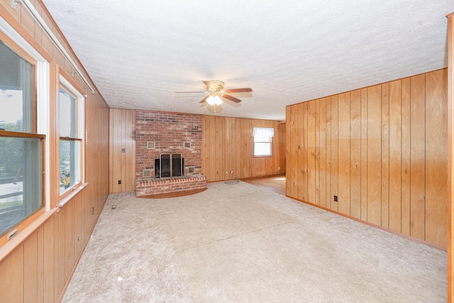 unfurnished living room featuring a brick fireplace, wooden walls, and light colored carpet