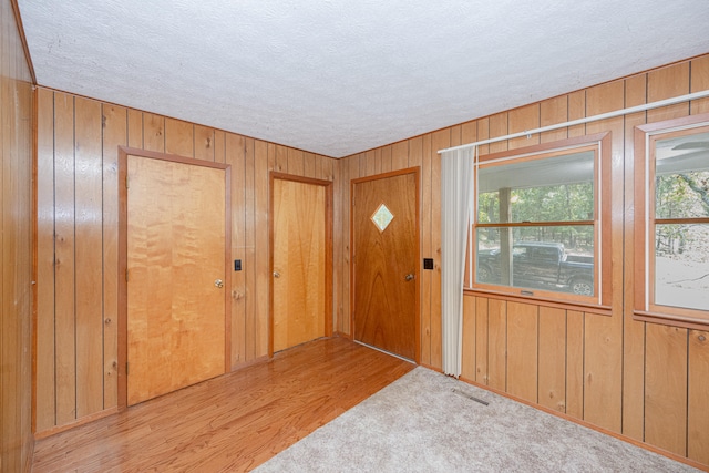 entrance foyer with wood walls, light hardwood / wood-style floors, and a textured ceiling