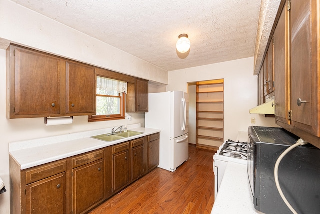 kitchen featuring sink, a textured ceiling, dark hardwood / wood-style flooring, and white appliances