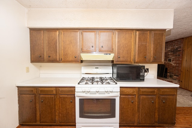 kitchen featuring wood-type flooring, brick wall, white gas range, and a textured ceiling