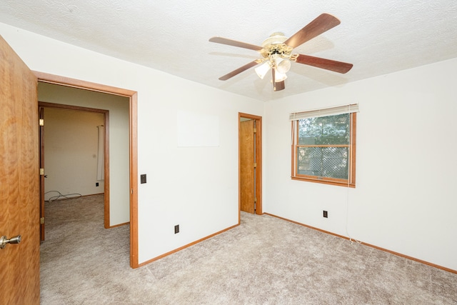 unfurnished bedroom featuring light colored carpet, a textured ceiling, and ceiling fan