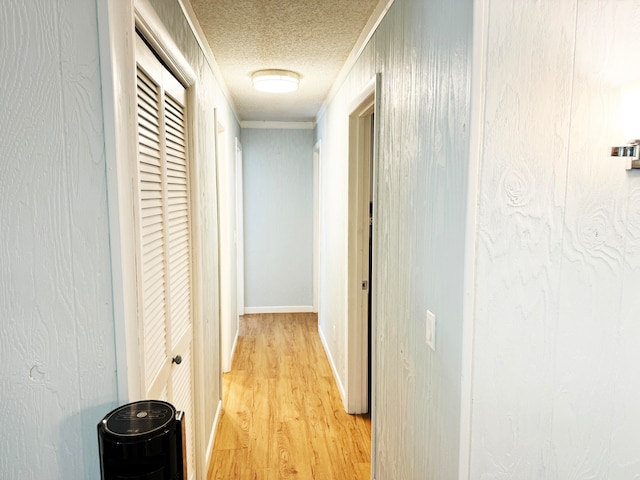 hallway with light hardwood / wood-style floors and a textured ceiling