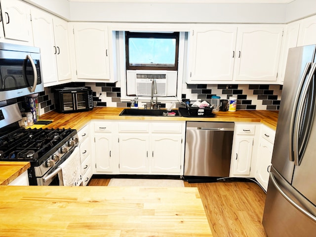 kitchen featuring appliances with stainless steel finishes, white cabinetry, decorative backsplash, and wood counters