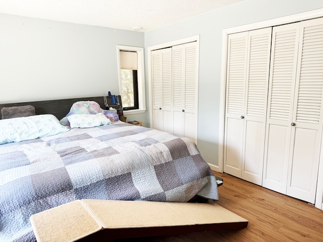 bedroom featuring multiple closets, hardwood / wood-style flooring, and a textured ceiling