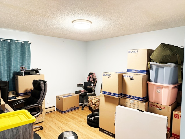 home office with baseboard heating, light wood-type flooring, and a textured ceiling