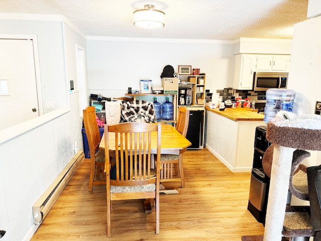 dining space with a baseboard radiator, crown molding, light hardwood / wood-style floors, and a textured ceiling