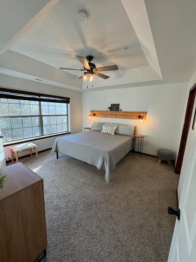 carpeted bedroom featuring a raised ceiling and ceiling fan