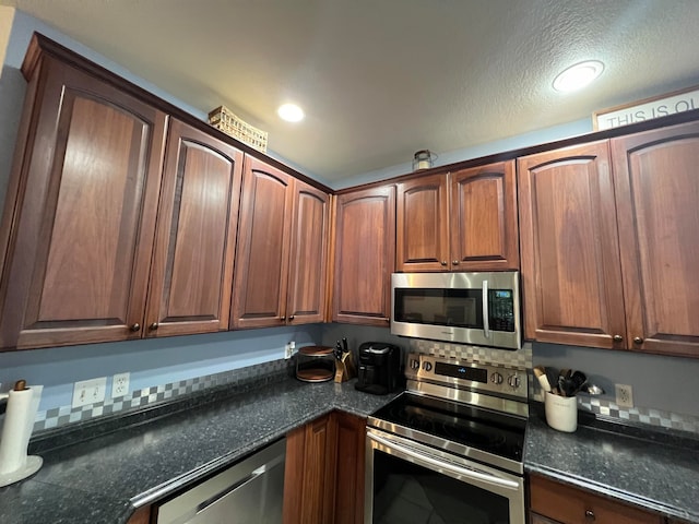 kitchen with appliances with stainless steel finishes, a textured ceiling, and dark stone counters