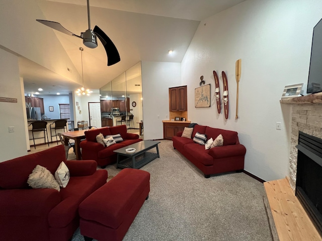 carpeted living room with ceiling fan with notable chandelier, a fireplace, and high vaulted ceiling