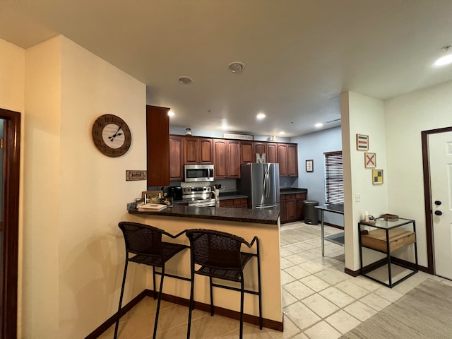 kitchen featuring stainless steel appliances, a kitchen breakfast bar, kitchen peninsula, decorative backsplash, and light tile patterned floors