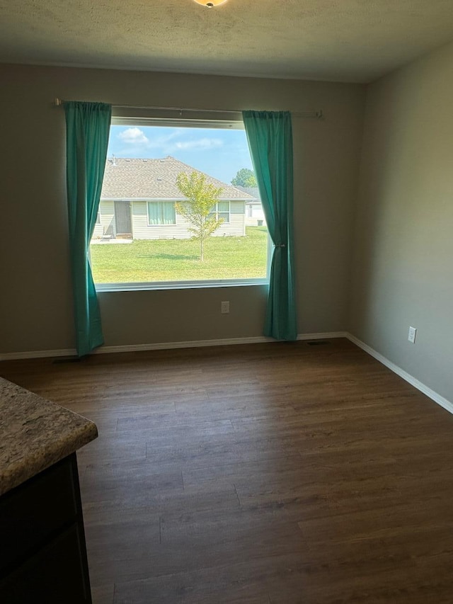 empty room with dark hardwood / wood-style floors and a textured ceiling