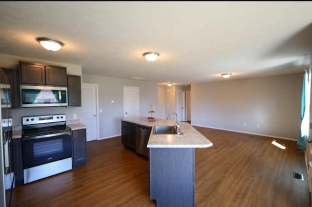 kitchen featuring appliances with stainless steel finishes, sink, an island with sink, dark brown cabinets, and dark hardwood / wood-style floors