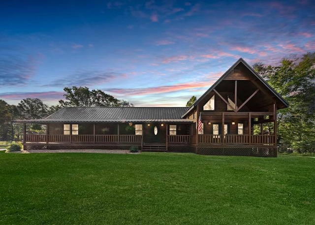 back house at dusk featuring a lawn