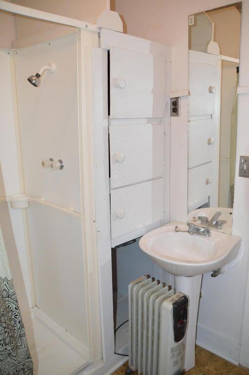 bathroom featuring walk in shower, tile patterned flooring, sink, and radiator heating unit