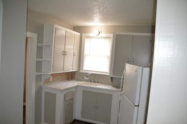 kitchen with white fridge, sink, and a textured ceiling