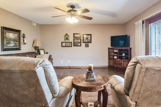 living area with baseboards, wood finished floors, and ceiling fan