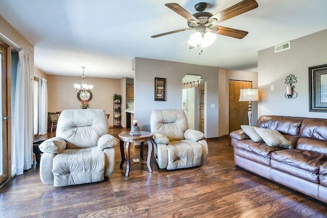 living room with ceiling fan with notable chandelier and dark hardwood / wood-style flooring