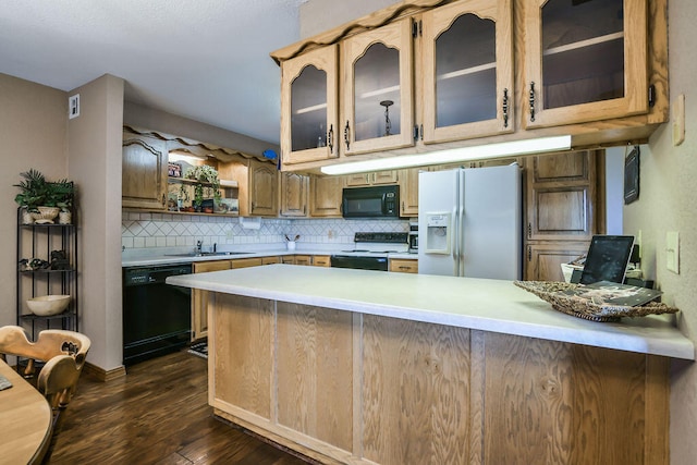 kitchen with dark hardwood / wood-style floors, kitchen peninsula, tasteful backsplash, and black appliances