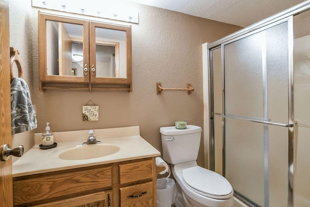 bathroom with a textured ceiling, a shower with door, vanity, and toilet