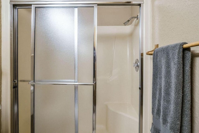 bathroom featuring a textured wall and a stall shower