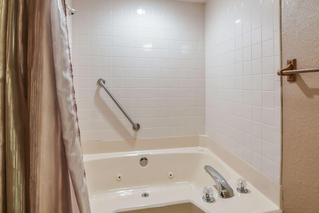 bathroom featuring a textured wall and a combined bath / shower with jetted tub