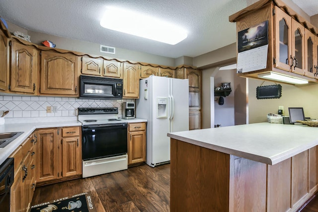 kitchen with kitchen peninsula, tasteful backsplash, a textured ceiling, black appliances, and dark hardwood / wood-style floors