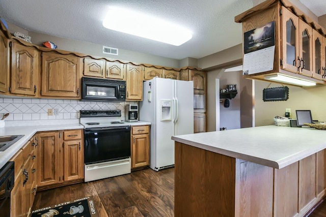 kitchen featuring visible vents, glass insert cabinets, light countertops, dark wood-type flooring, and black appliances